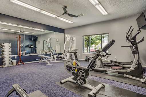 A gym with a variety of equipment including a rowing machine.