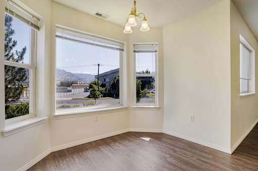 A room with a view of a street and houses outside the window.