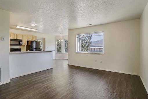A spacious room with wooden floors and a large window.