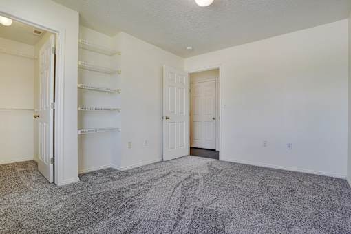 A large, empty room with a grey carpet and white walls.