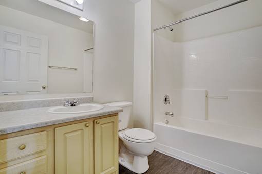 A white toilet sits in a bathroom next to a sink and bathtub.