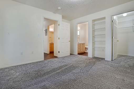 A spacious room with white walls and a grey carpet.
