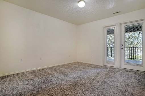 A room with a carpeted floor and a door leading outside.