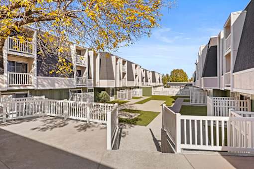 a row of apartments with white fences and lawns