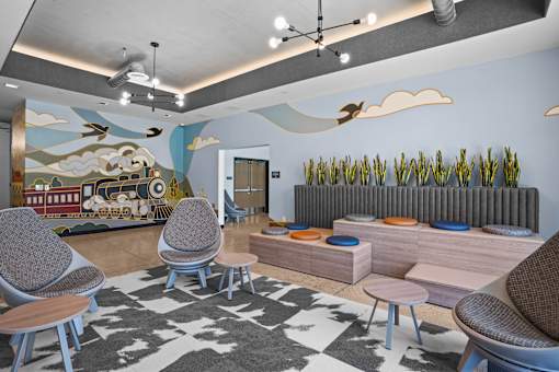 A room with a mural of a train and clouds on the wall, a radiator, and a patterned rug on the floor.