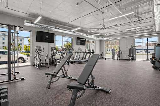 A gym with a row of treadmills and a television mounted on the wall.