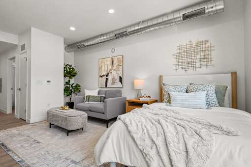 A bedroom with a large bed and a grey couch.