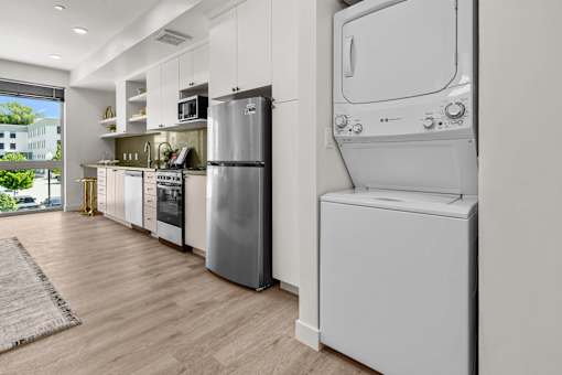 A modern kitchen with a refrigerator, oven, and washing machine.