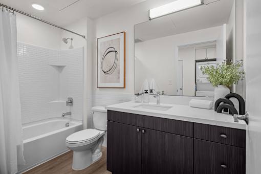 A white bathroom with a toilet, sink, and a large mirror.