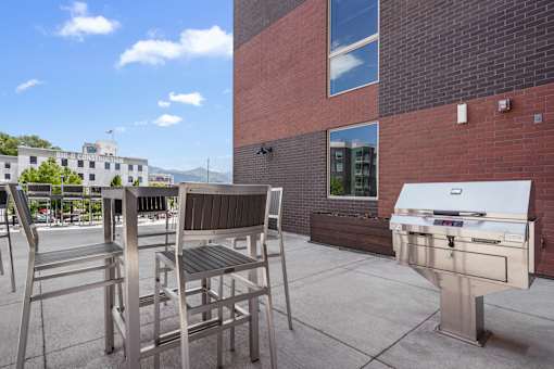 A patio with a grill and chairs.