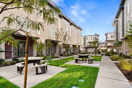 a courtyard with benches and picnic tables in front of apartments