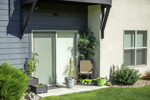a patio with a chair and potted plants in front of a house