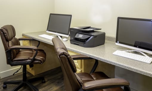 a desk with two computers and two chairs