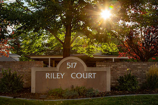 A sign that says Riley Court in front of a tree.
