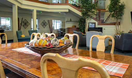 A wooden dining table with a bowl of fruit on it.