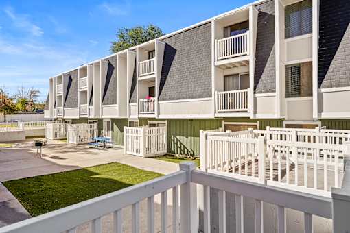 A white fence surrounds a building with balconies.
