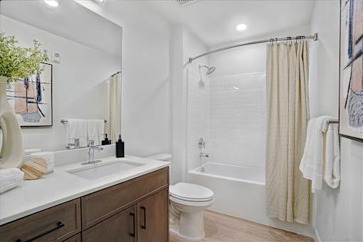A bathroom with a white toilet, sink, and shower.