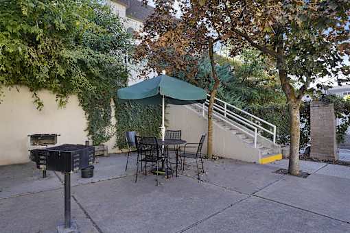 A patio with a table and chairs under a green umbrella.