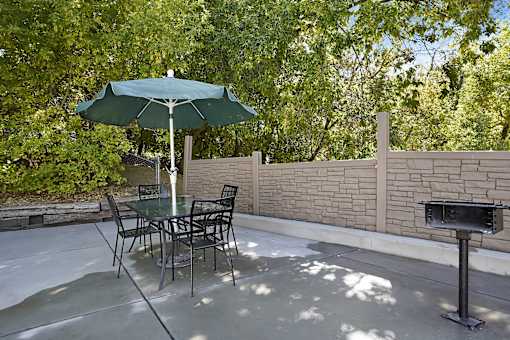 A patio with a table and chairs and an umbrella.