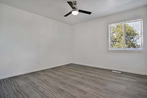 A room with a ceiling fan and a window with blinds.