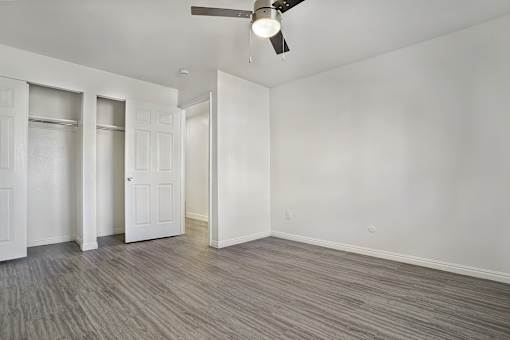 A room with a ceiling fan and wood flooring.