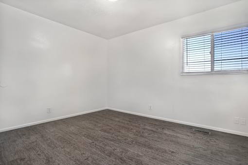 A room with a window and wooden flooring.