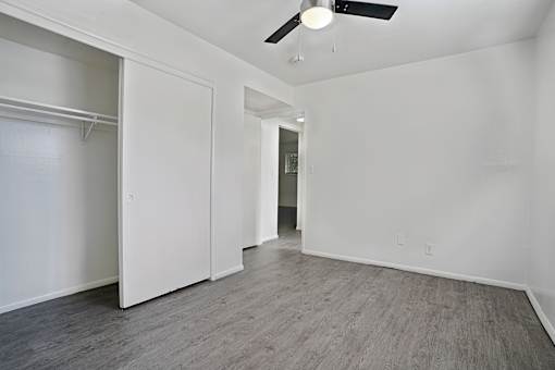 A room with a ceiling fan and a doorway leading to another room.