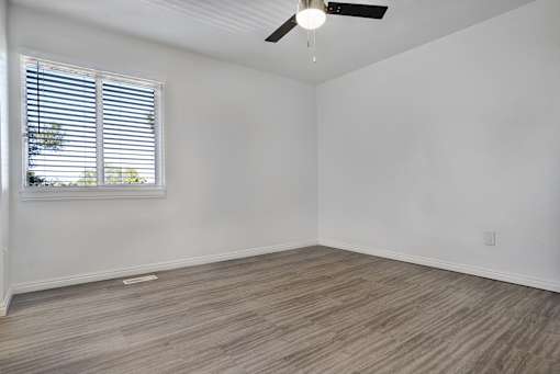 A room with a ceiling fan and a window with blinds.