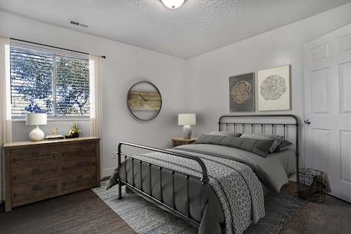A bedroom with a bed, nightstand, and window.