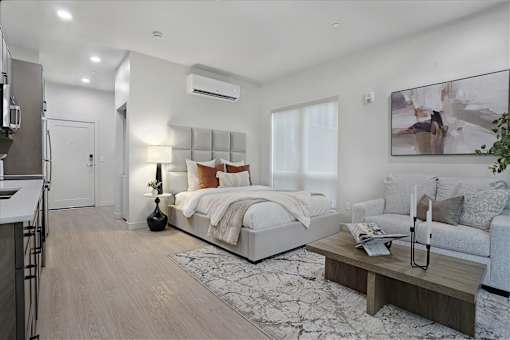 A modern bedroom with a large bed and a kitchen area.
