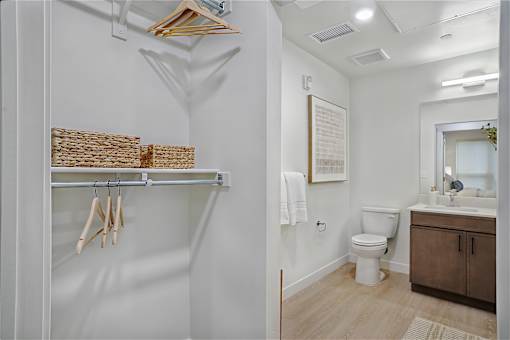 A bathroom with a toilet, sink, and clothes hanging up.