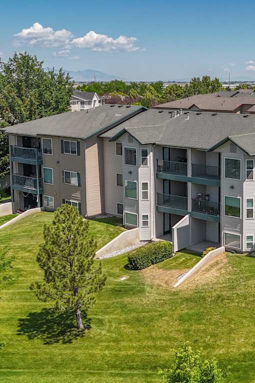 Apartment complex with a green lawn and trees.