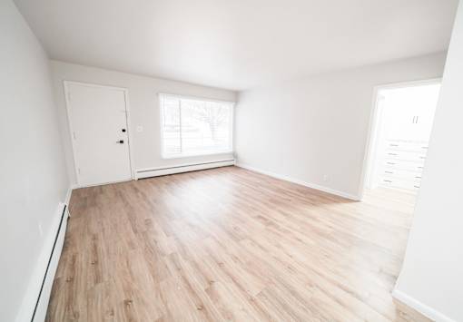 A room with wooden flooring and white walls.