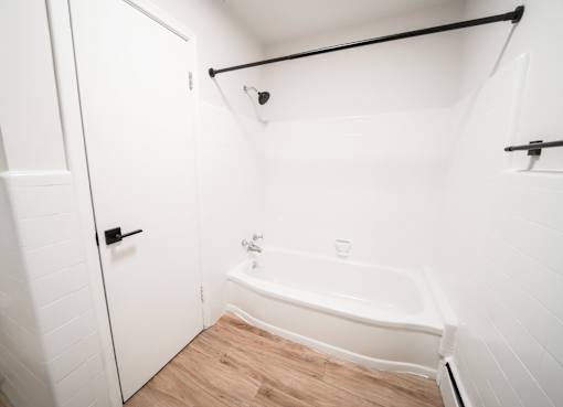 A white bathroom with a tub and a door.