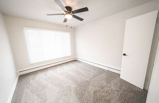 A room with a ceiling fan and a window with blinds.