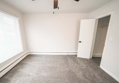 A room with a carpeted floor and a ceiling fan.