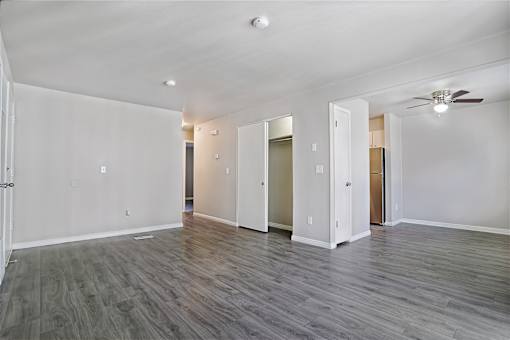 A spacious room with a ceiling fan and wooden flooring.