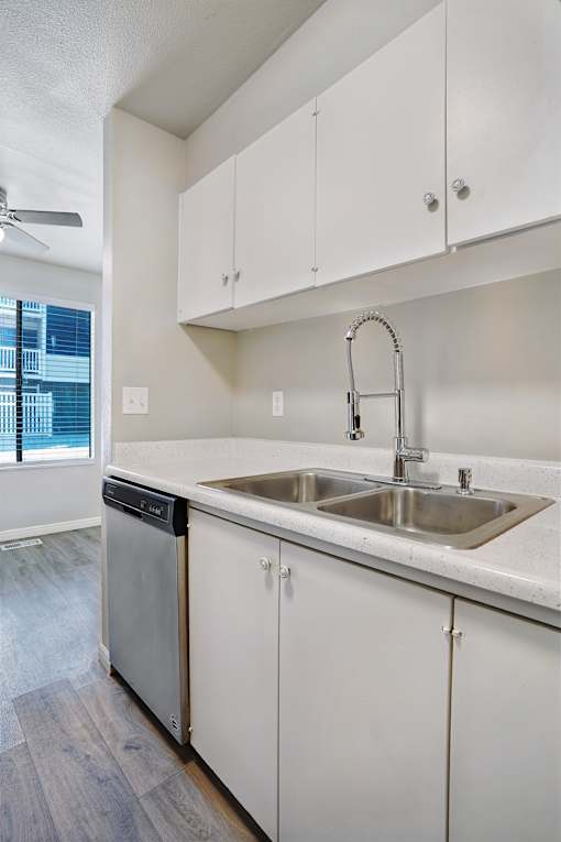 A modern kitchen with white cabinets and a stainless steel dishwasher.