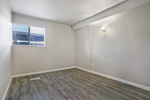A room with a window and a wooden floor.