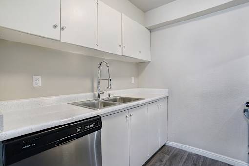 A kitchen with white cabinets and a black dishwasher.