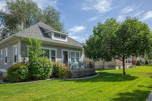 a house with a large lawn and trees in front of it