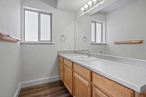 A bathroom with a sink, mirror, and wooden cabinets.