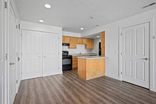 A kitchen with white walls and wooden floors.