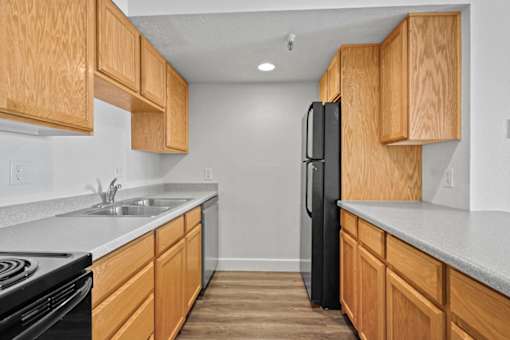 A kitchen with wooden cabinets and a black refrigerator.