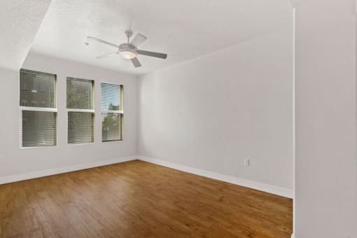 an empty living room with a ceiling fan and wood floors