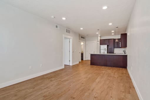 an empty living room and kitchen with a hard wood floor