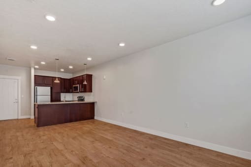 an empty living room and kitchen with wood flooring