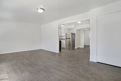 A spacious room with a kitchen area in the background.