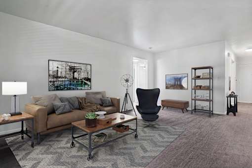 A living room with a brown couch, a black chair, and a grey rug.