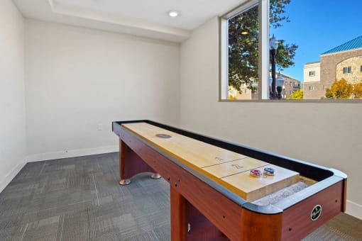 a game room with a shuffleboard table and a window